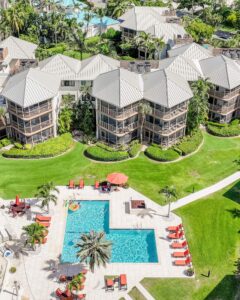 An aerial view of a pool and buildings at a Grand Cayman resort near shopping destinations.